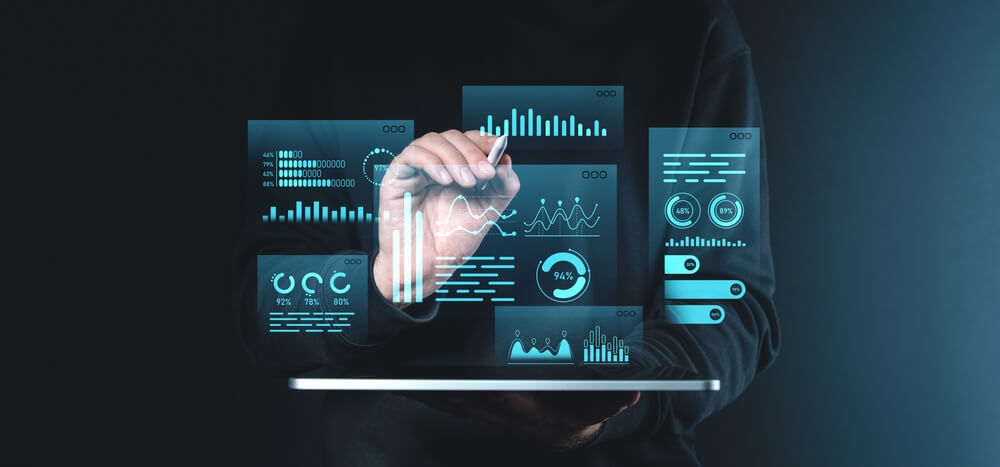 Persona interactuando con paneles digitales que muestran gráficos y métricas, ilustrando un flujo de trabajo de procesamiento por lotes en un entorno empresarial.
