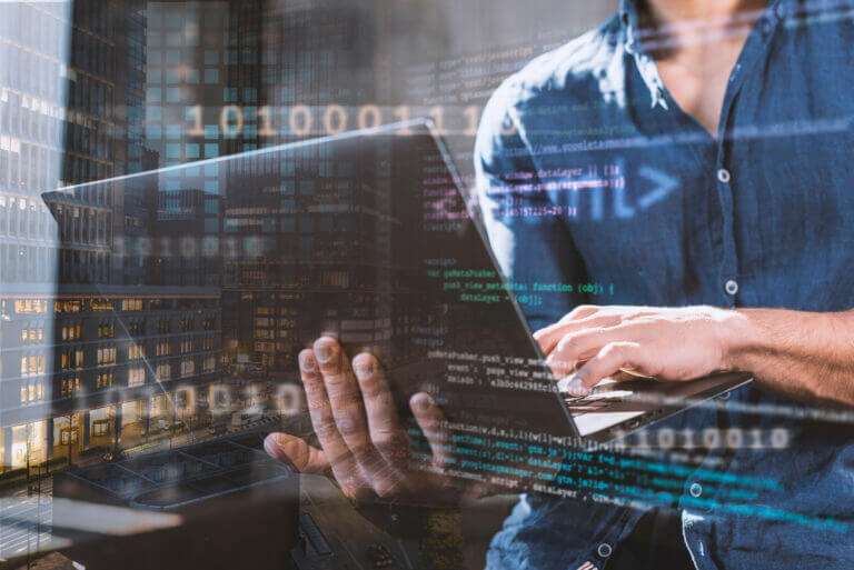 Profesional con laptop analizando datos en código y entorno urbano, representando los distintos tipos de Big Data.