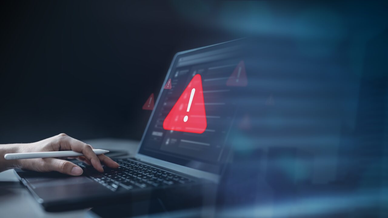 Laptop mostrando una señal de alerta roja, ilustrando la filtración de credenciales Fortinet FortiBleed en redes empresariales.