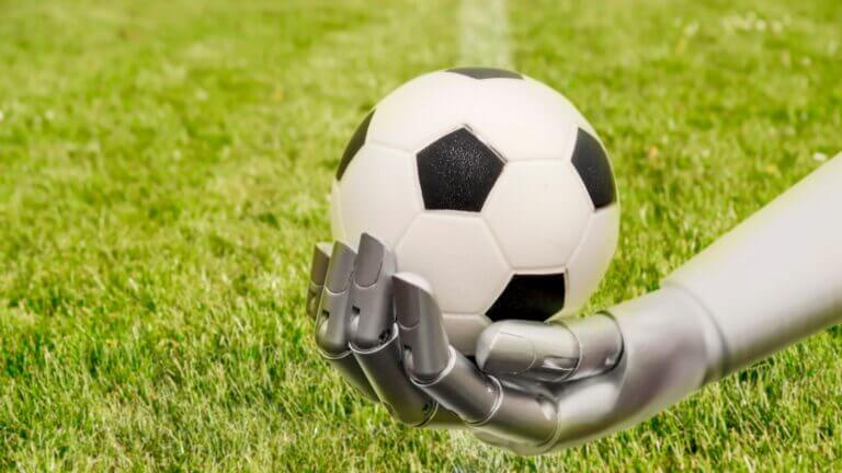 Mano robótica de plata sosteniendo un balón de fútbol clásico en césped, ilustrando la AI Mundial 2026.