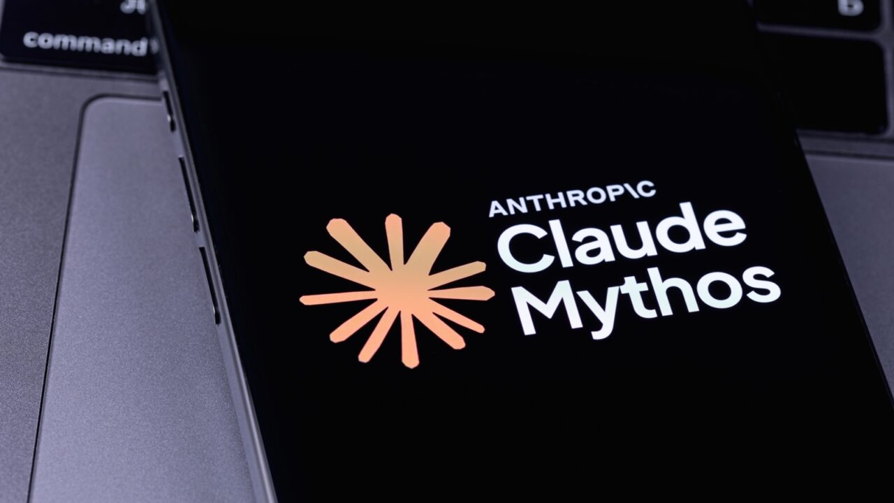 Pantalla de smartphone que muestra el logotipo de Anthropic Claude Mythos sobre el teclado de una computadora portátil.