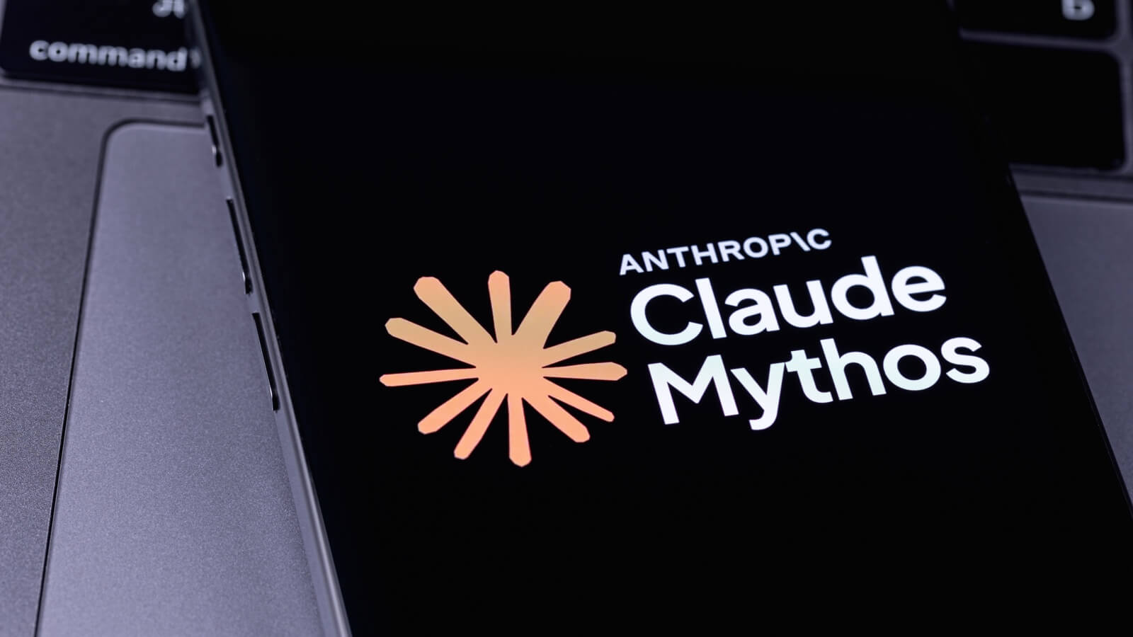 Pantalla de smartphone que muestra el logotipo de Anthropic Claude Mythos sobre el teclado de una computadora portátil.