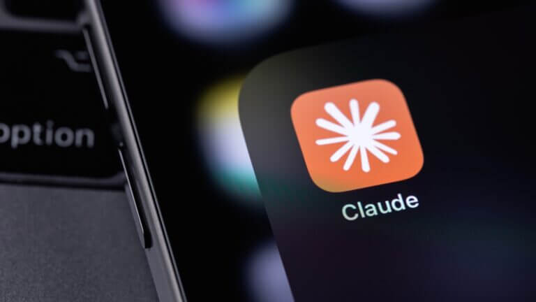 Icono de la aplicación Claude de Anthropic en la pantalla de un smartphone sobre el teclado de un ordenador.