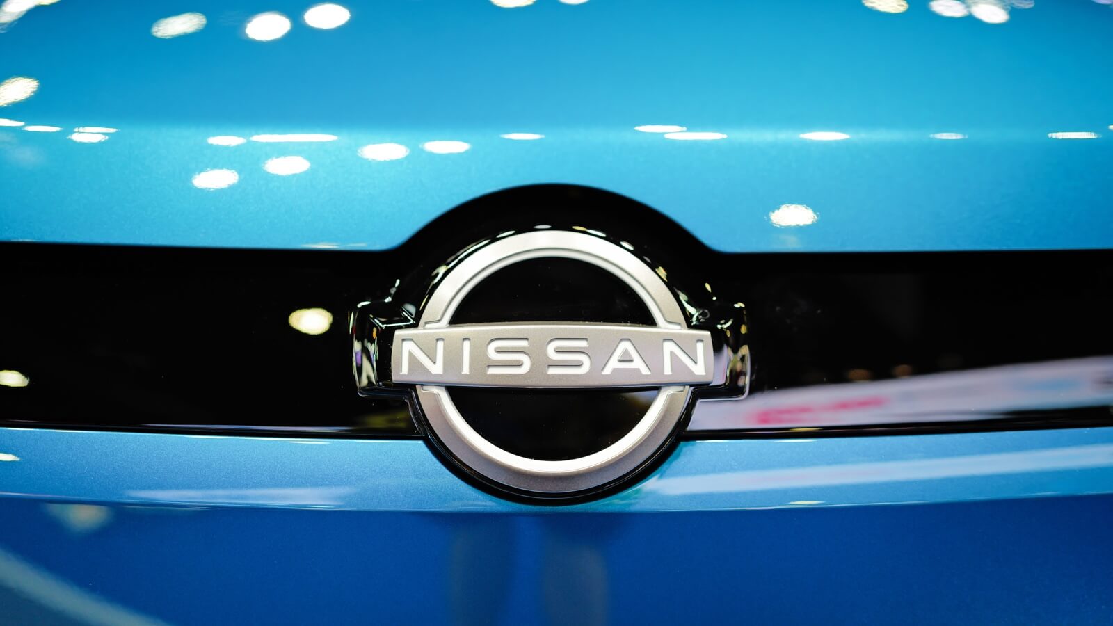Logotipo cromado de la marca sobre el cofre azul de un auto, ilustrando la filtración de datos Nissan Oracle.
