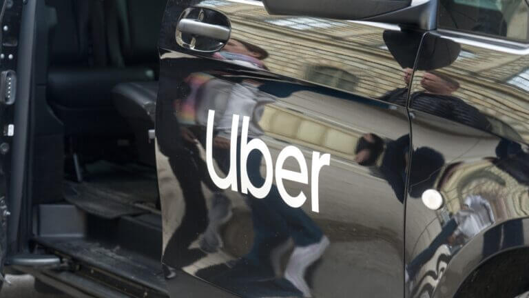 Vehículo negro con el logotipo de Uber impreso en la puerta lateral, ilustrando los recortes de personal por AI.