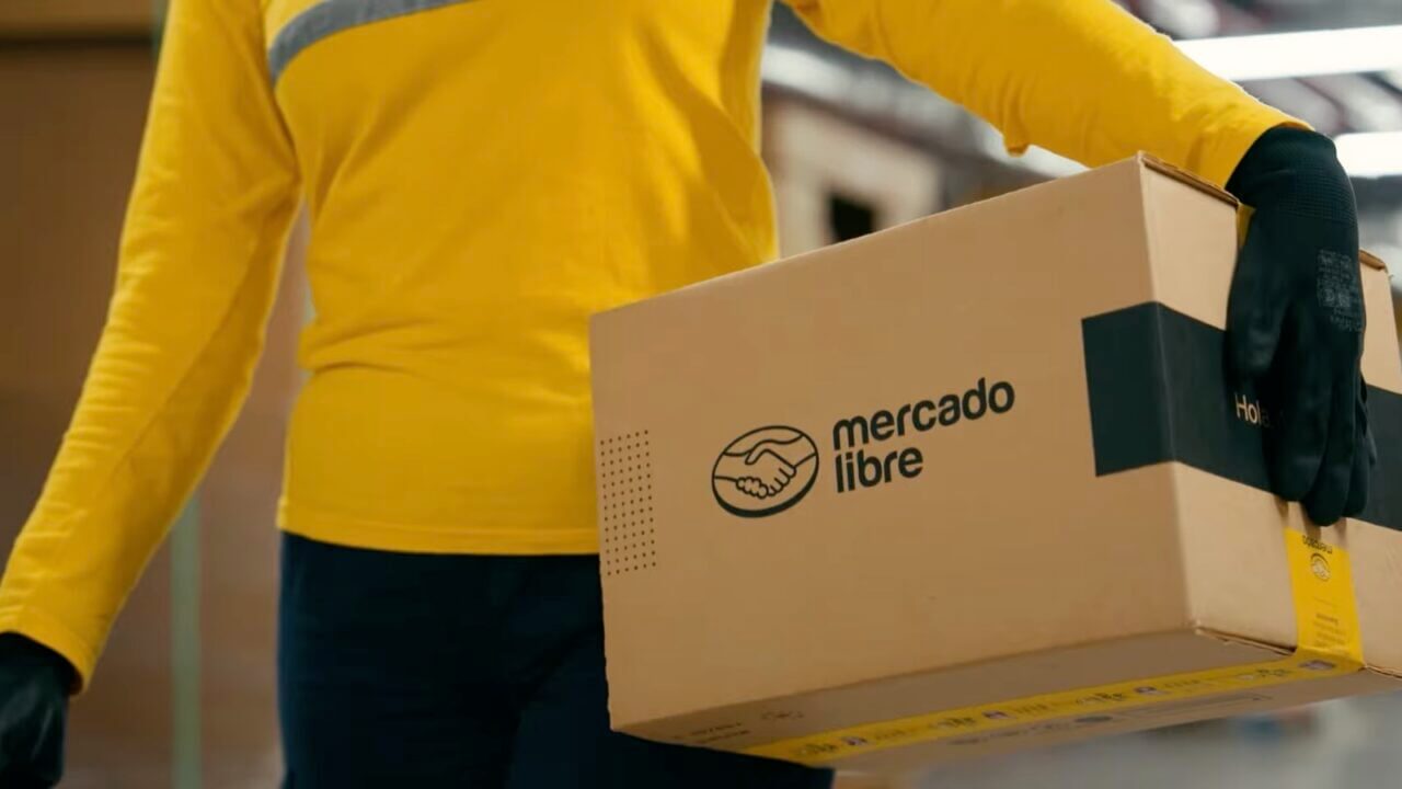 Trabajador de Mercado Libre sosteniendo un paquete en un centro logístico en el marco del desarrollo de software e AI.