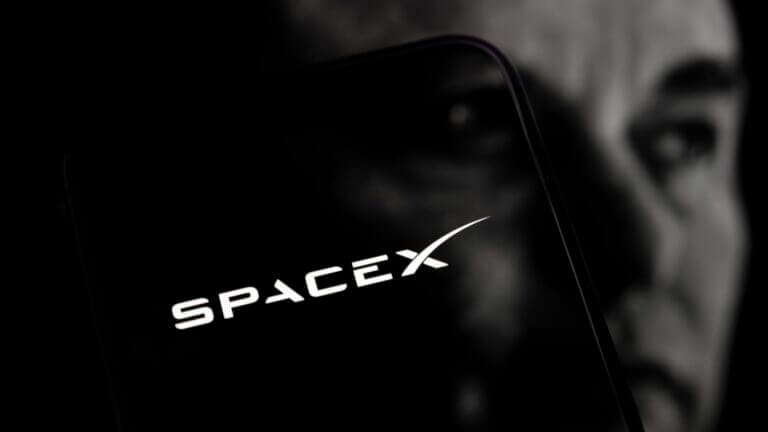 Logo de SpaceX en smartphone sobre rostro de Elon Musk, ilustrando la SpaceX alianza Nvidia AI.