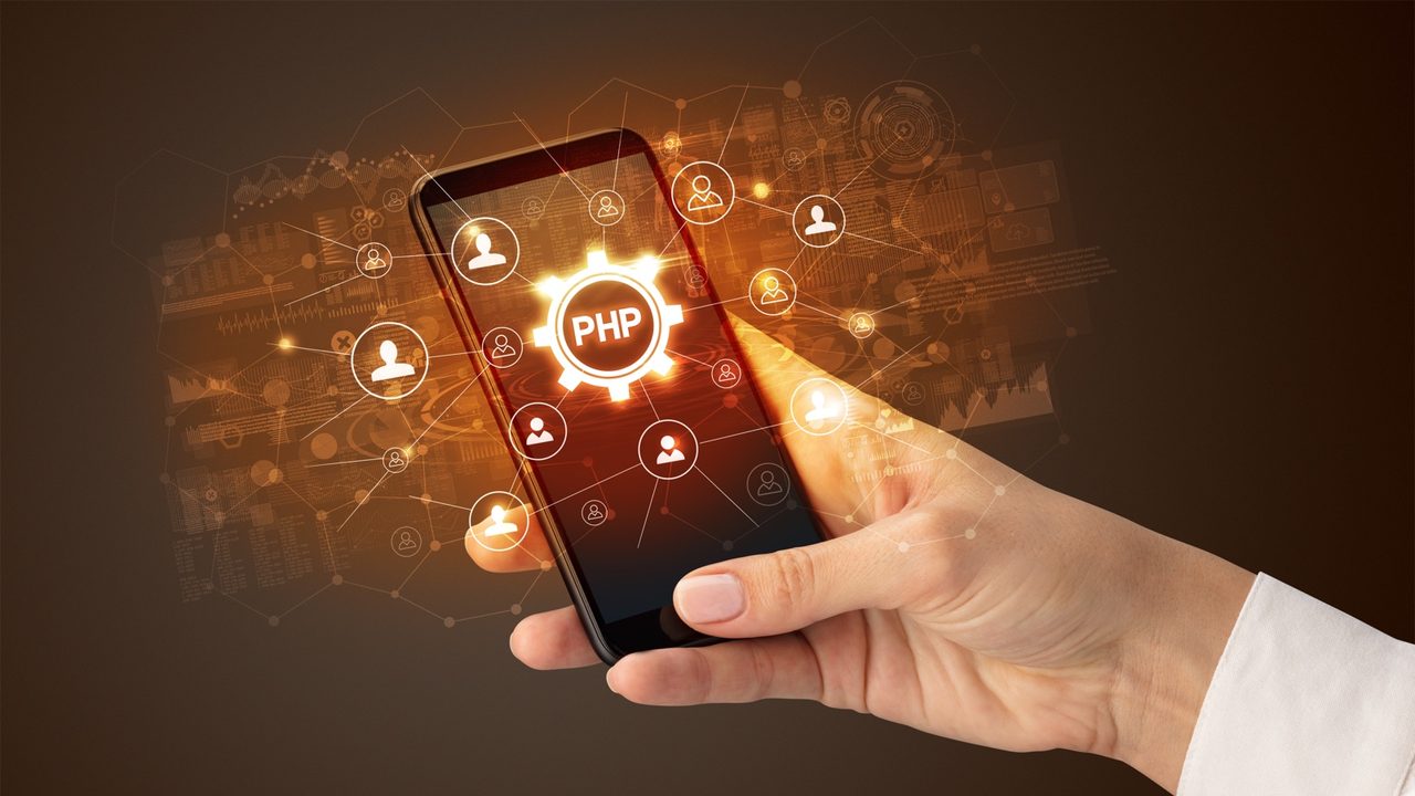 Mano sosteniendo un smartphone con el logotipo de PHP en pantalla para aplicar parches PHP2Shell vulnerabilidad.