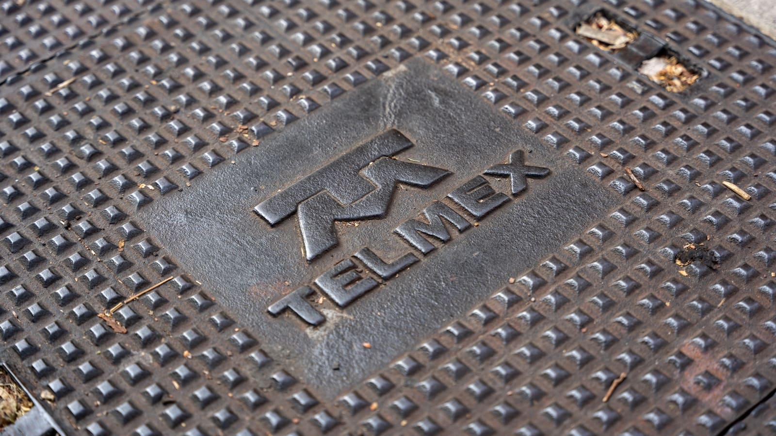Tapa de registro metálica de Telmex en la calle, filial de América Móvil que busca ofrecer cuádruple play.